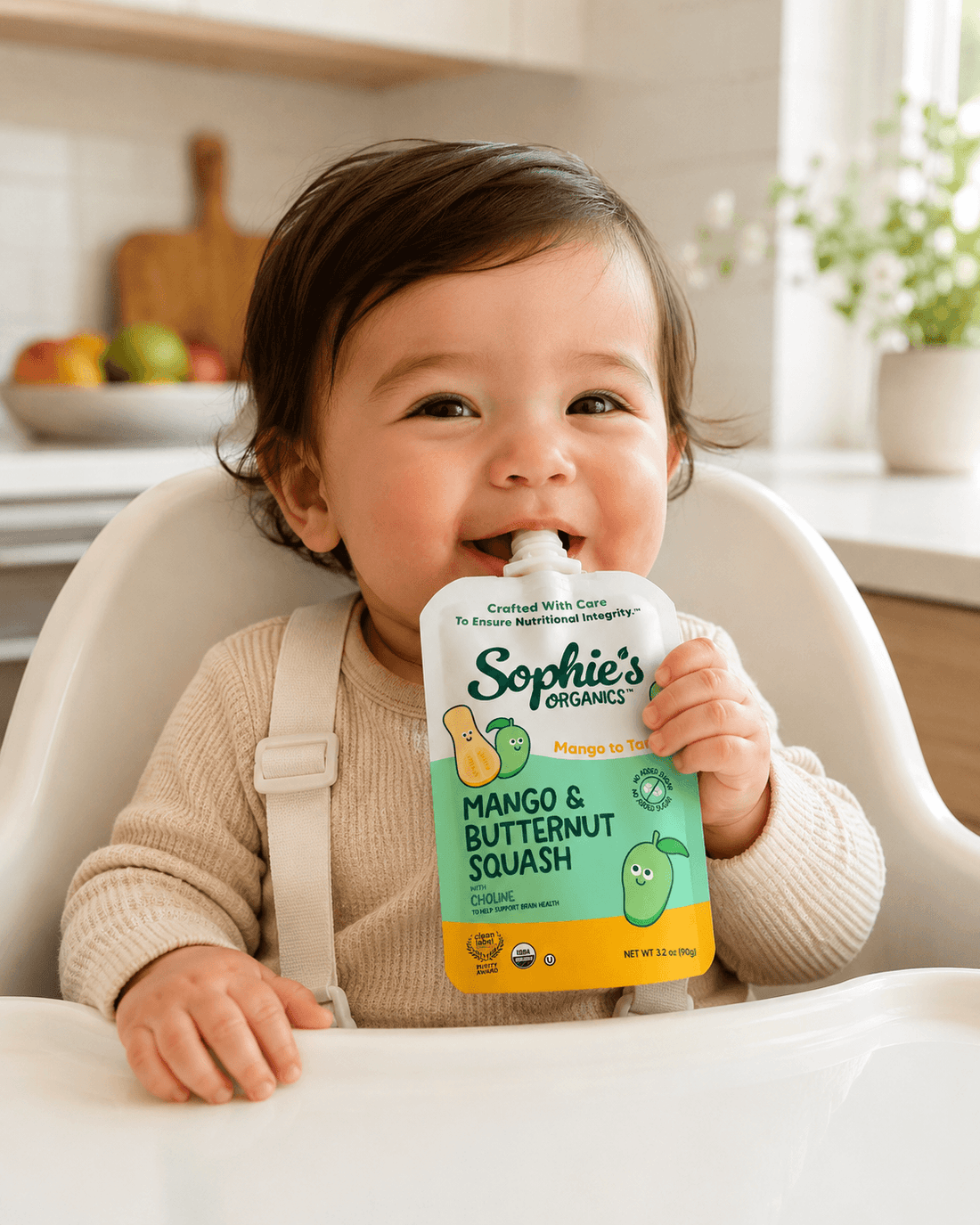 Baby eating a Sophie's Organics Mango To Tango pouch in a high chair