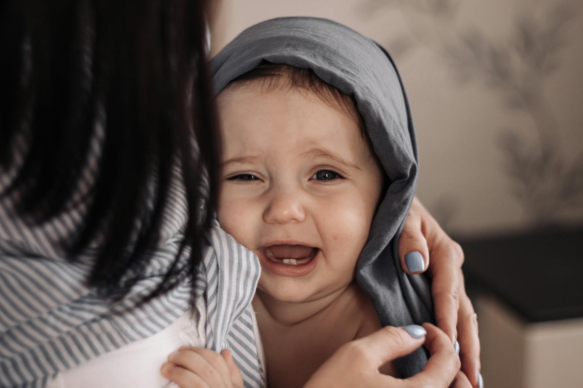 baby being held by mom and crying